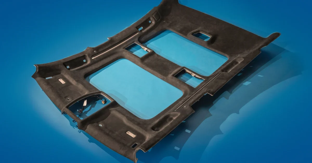 A molded automotive headliner on a blue background, with large roof openings and cutouts for interior fittings.