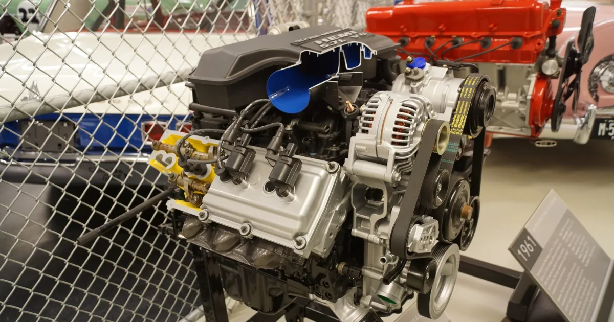 A 5.7 liter Hemi V8 on a display stand, with its black intake manifold on top and part of it cut away to show a blue runner inside