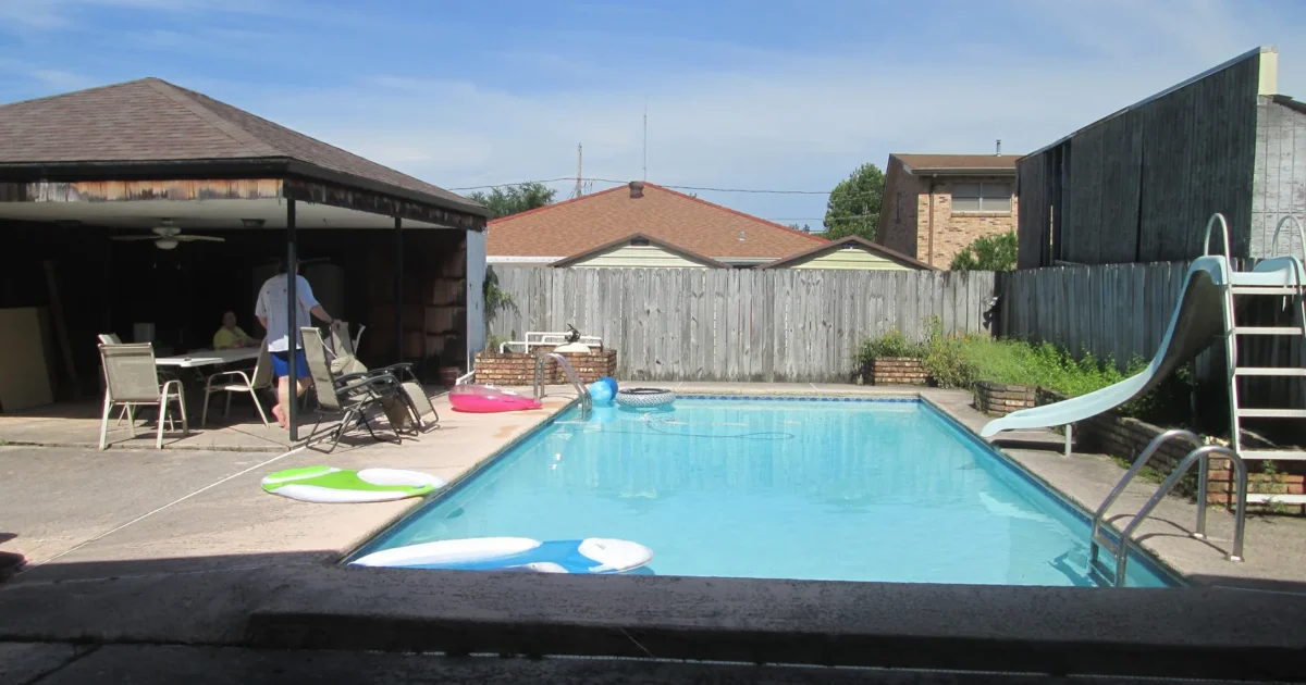 A rectangular backyard swimming pool beside a house in Metairie, Louisiana.