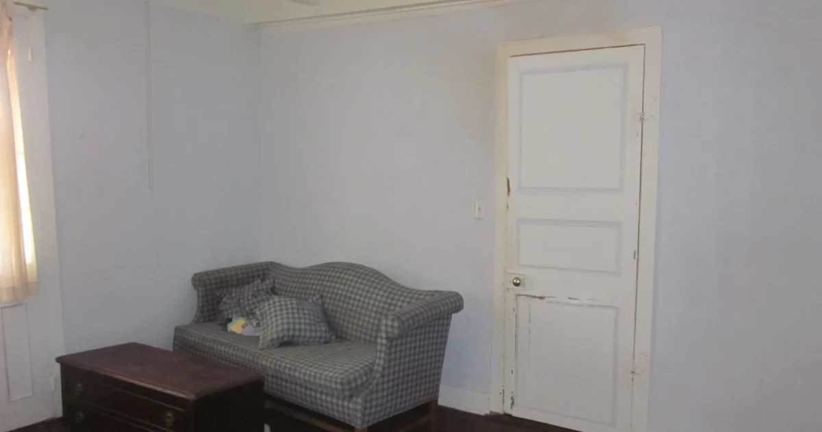 Painted interior door and surrounding trim beside a settee in a historic Louisiana bedroom.