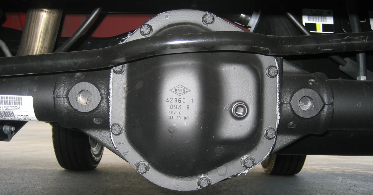 The rear axle of a Jeep Wrangler seen from behind, with the round differential cover in the middle and the axle tubes going out to the wheels