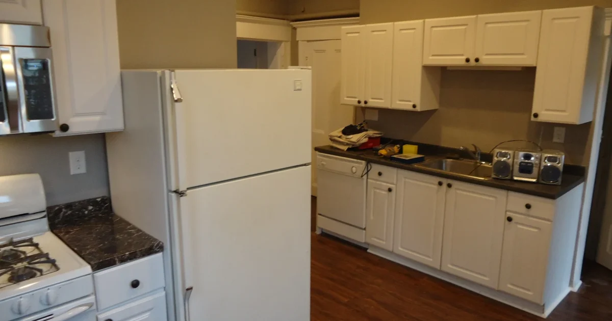 A kitchen with white cabinets, counters and wood flooring, with tools still on the countertop.