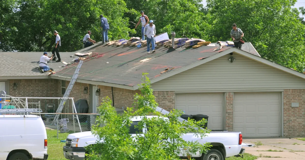 Workers replacing shingles on a house roof in Oklahoma.