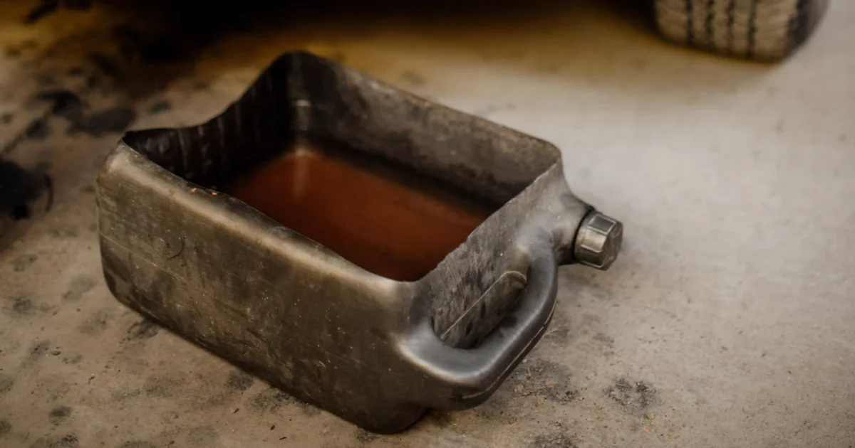 An oil drain pan below the front of a truck during an oil change in a workshop.