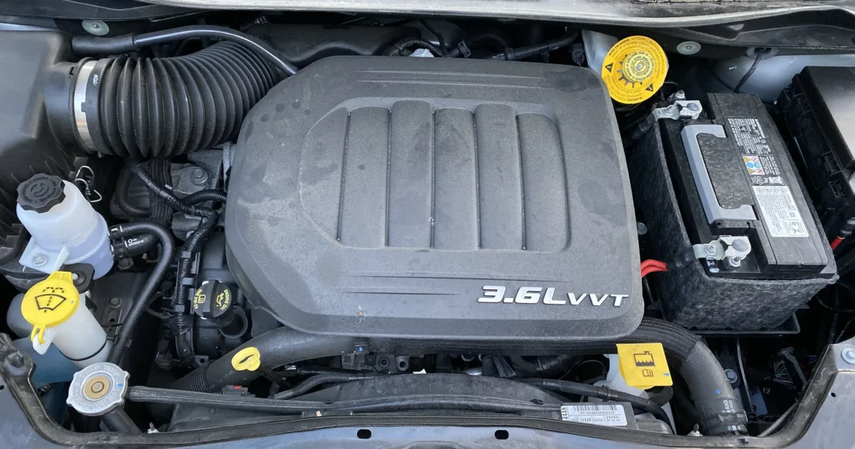 The engine bay of a Dodge Grand Caravan with a black engine cover marked 3.6L VVT