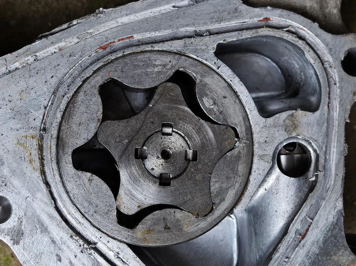 An opened oil pump housing with a star shaped inner gear sitting inside a round outer gear