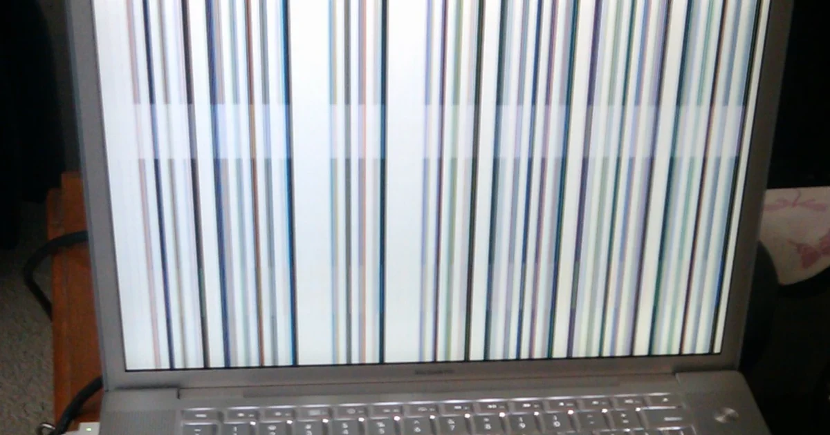 An older silver Mac laptop displaying vertical colored lines across its screen.