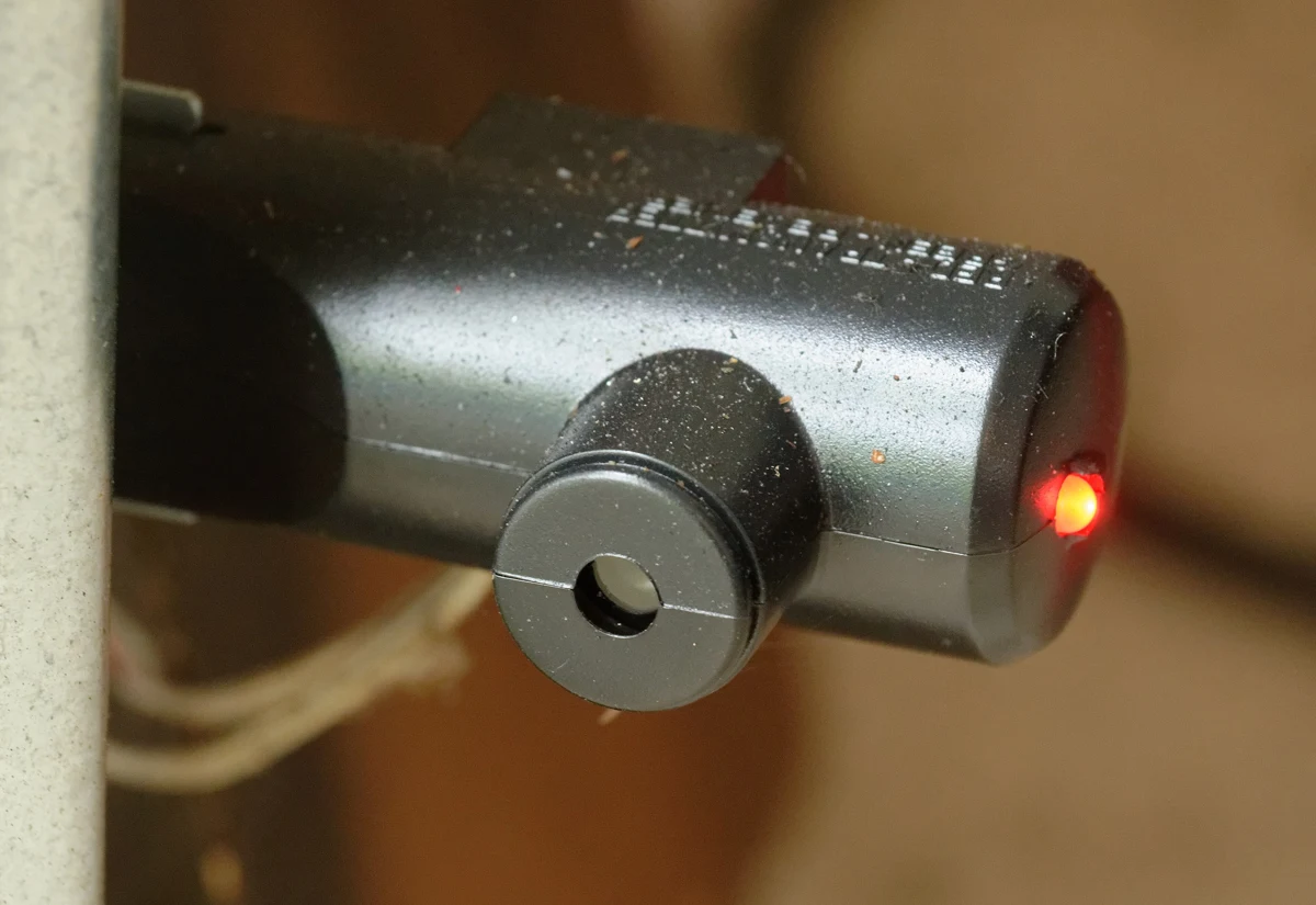 Close view of a garage-door photoelectric sensor with its indicator light on.