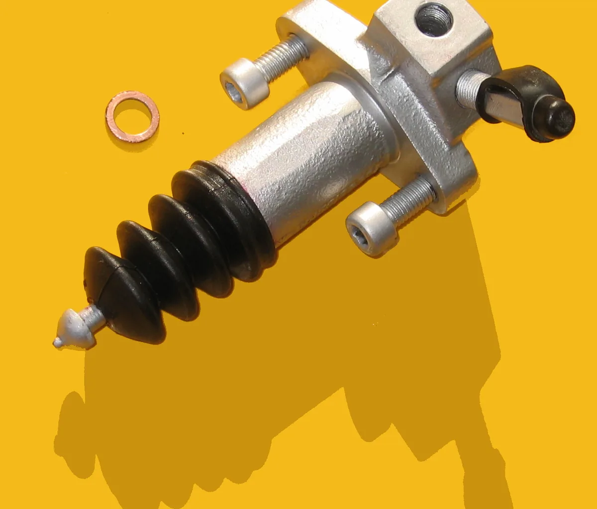 A clutch slave cylinder with a black rubber boot at one end, on a yellow background