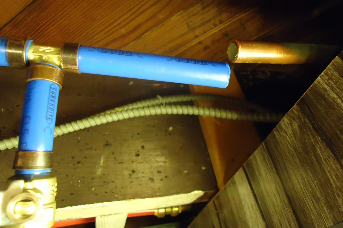 Blue PEX supply tubing and valves in a basement ceiling.