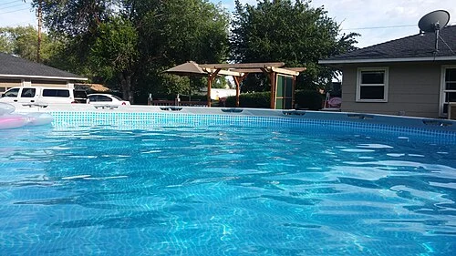 Water inside an above-ground pool with a patterned liner at the rim.