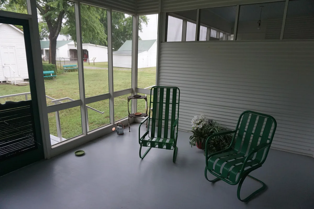 Green chairs and a doorway inside a screened porch at the Sam Rayburn House Museum.