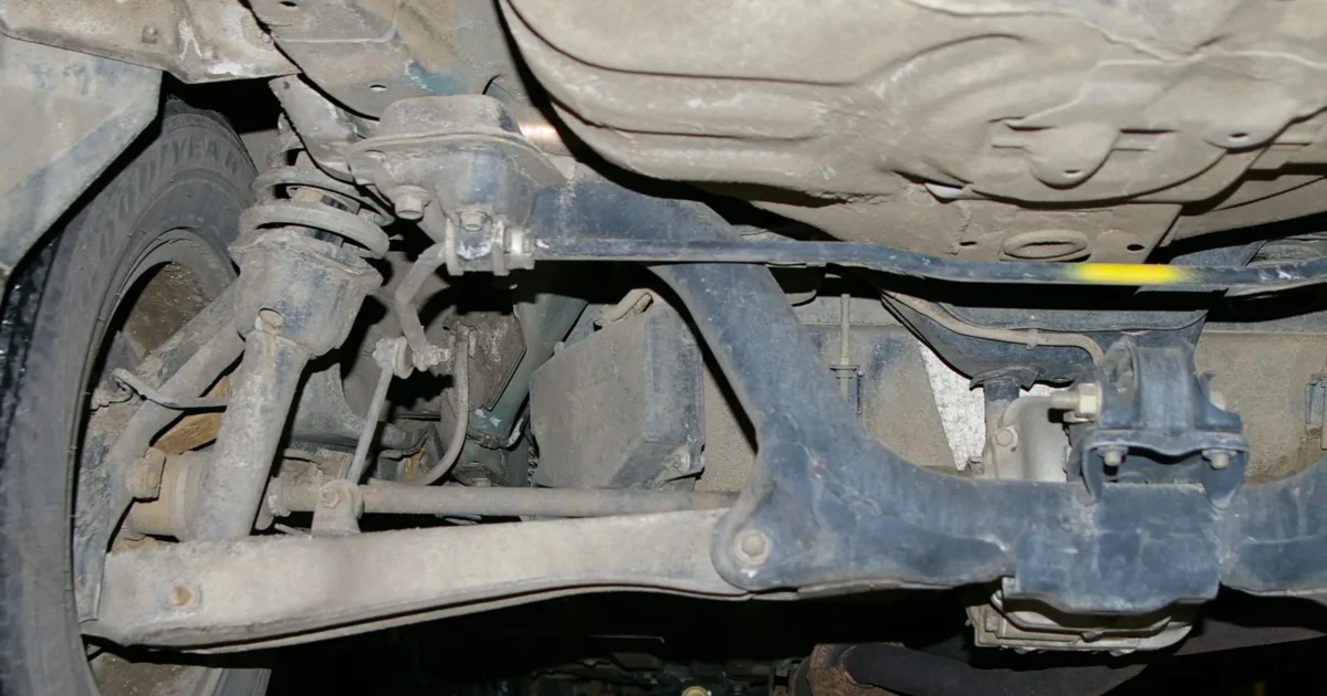 The underside of a car at the back, with a wheel on the left and the shock and coil spring beside it