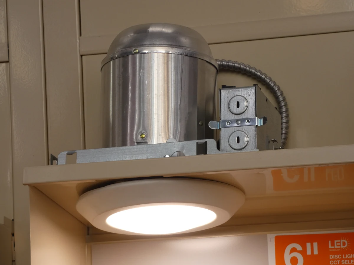 A store display exposes the metal can and electrical box above a recessed ceiling light.