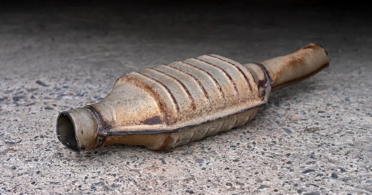 A removed metal catalytic converter and its adjoining exhaust pipe.