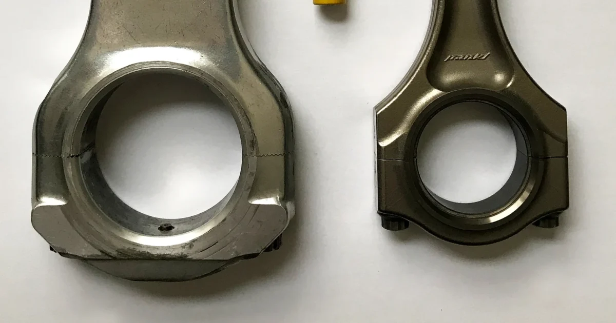 Close view of the large circular ends of a Top Fuel dragster connecting rod and a Ferrari 458 connecting rod.