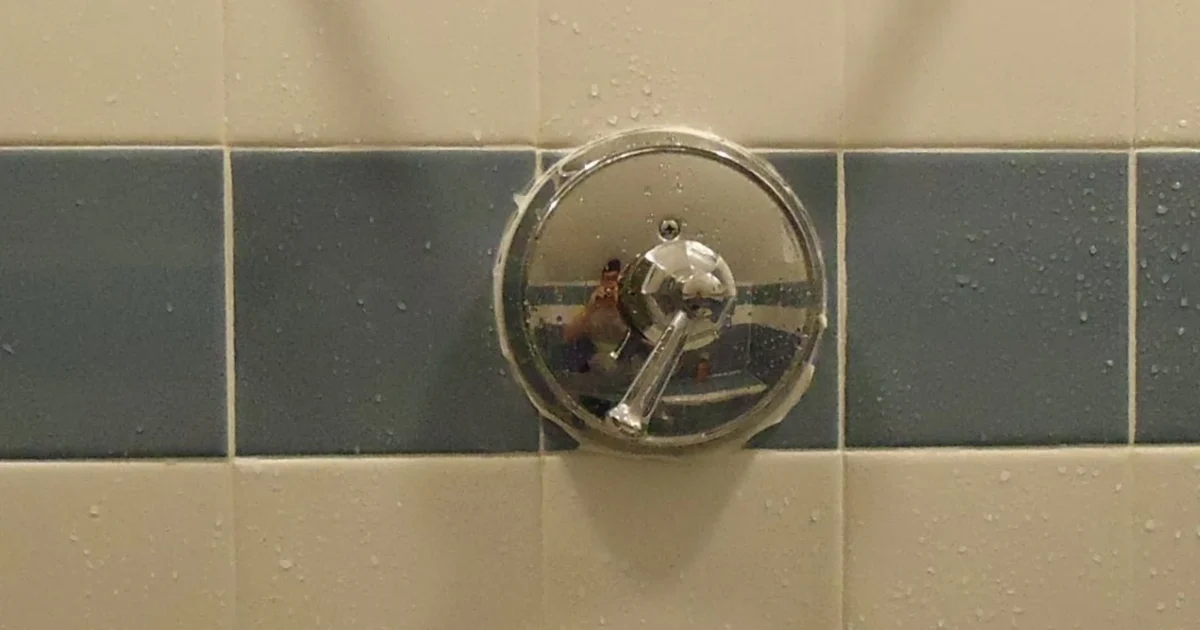 Chrome shower controls on a blue and white tiled shower wall.