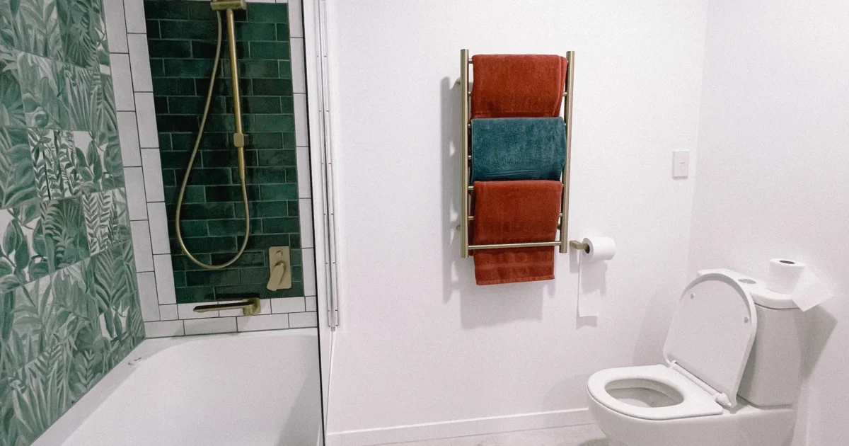A small renovated bathroom with a tub, shower, towel rail and toilet.