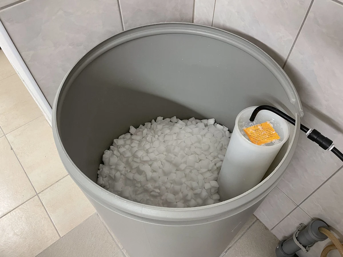Salt pellets in an open brine tank beside its internal well.