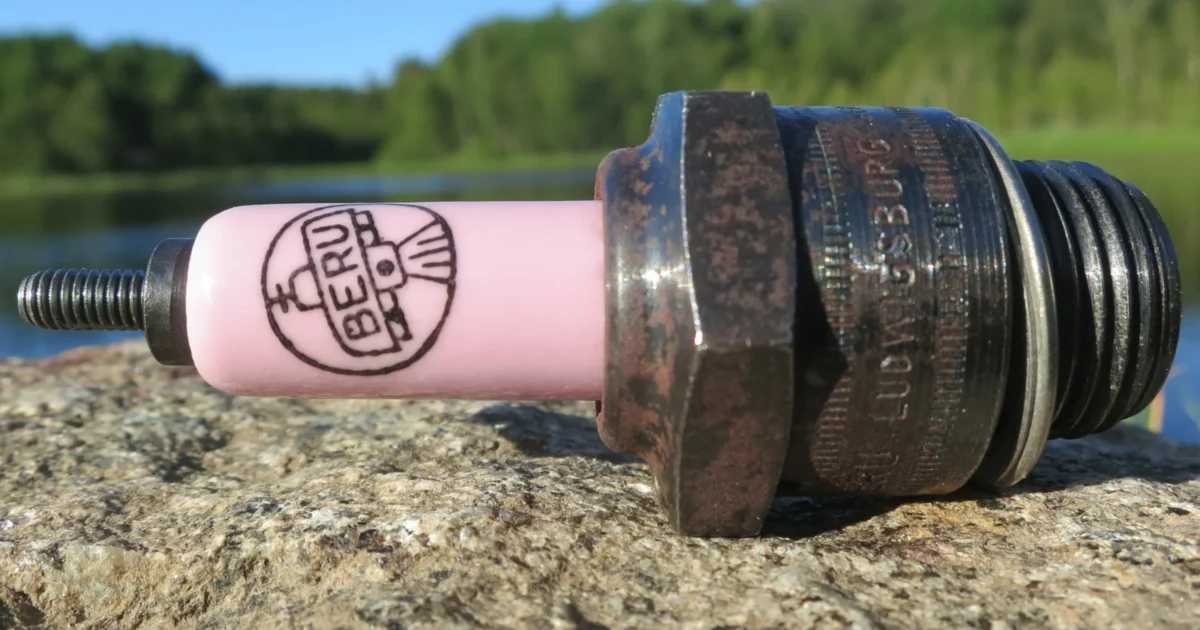 A vintage Beru spark plug with a pink ceramic insulator and threaded metal shell.