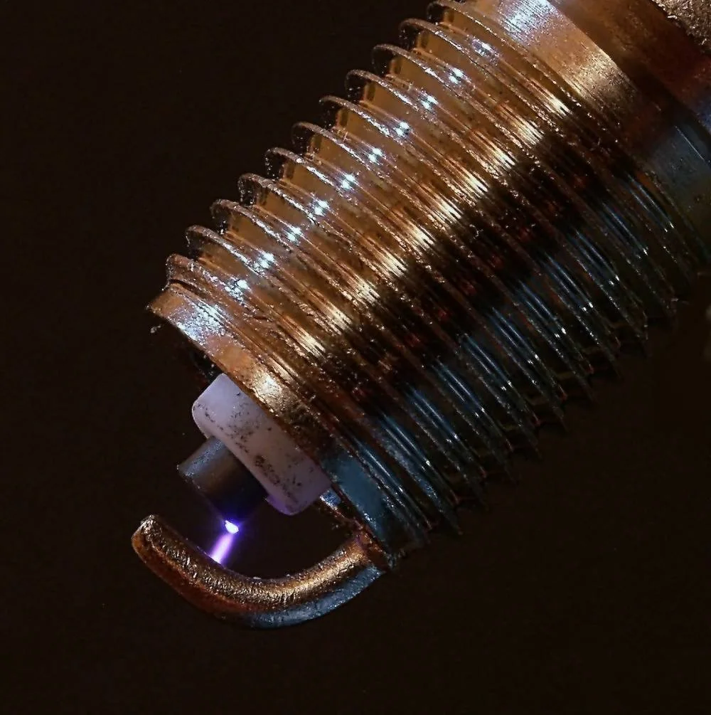 An electrical spark between a spark plug center tip and ground electrode.