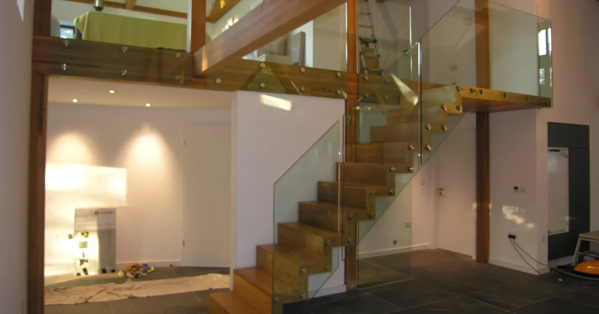 Wooden treads with glass guarding and steel supports in a contemporary interior.