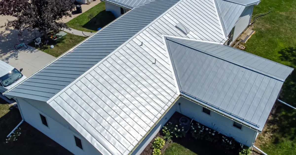 An aerial photograph of a house with a light-colored standing-seam metal roof.