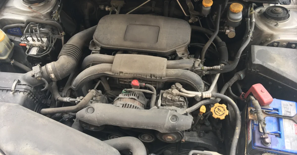 The engine bay of a 2011 Subaru Outback with the flat four engine, its intake on top and the battery on the right