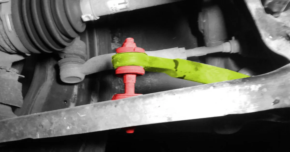 The front suspension of a small car seen from below, with the sway bar link colored red and the sway bar yellow