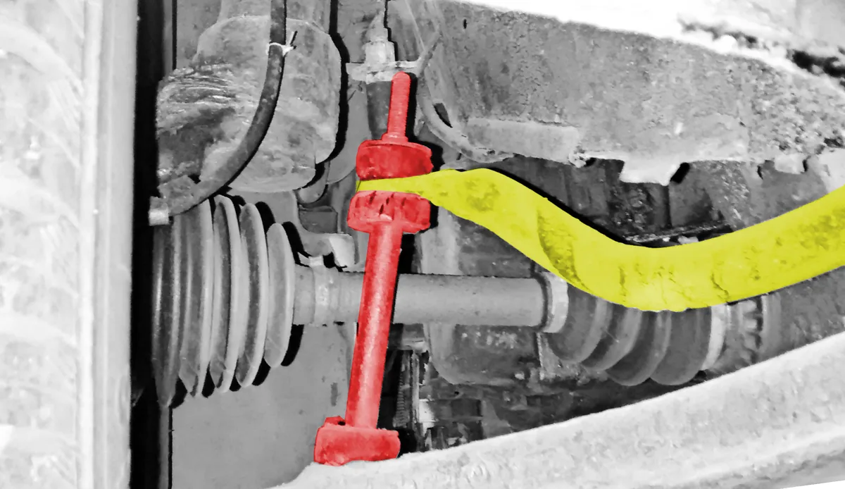 A sway bar link colored red joining a yellow sway bar to the front suspension, next to the drive shaft