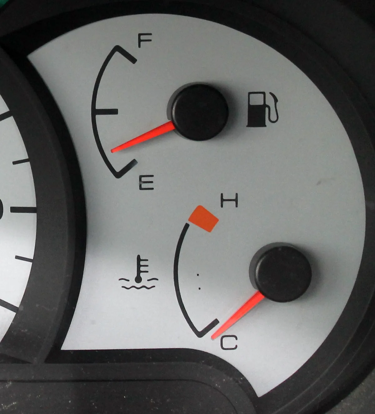 A white gauge cluster with the fuel gauge above and the coolant temperature gauge below, its needle down at C