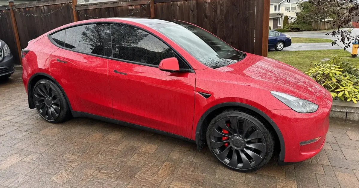 A red Tesla Model Y with dark ceramic tint on its side windows