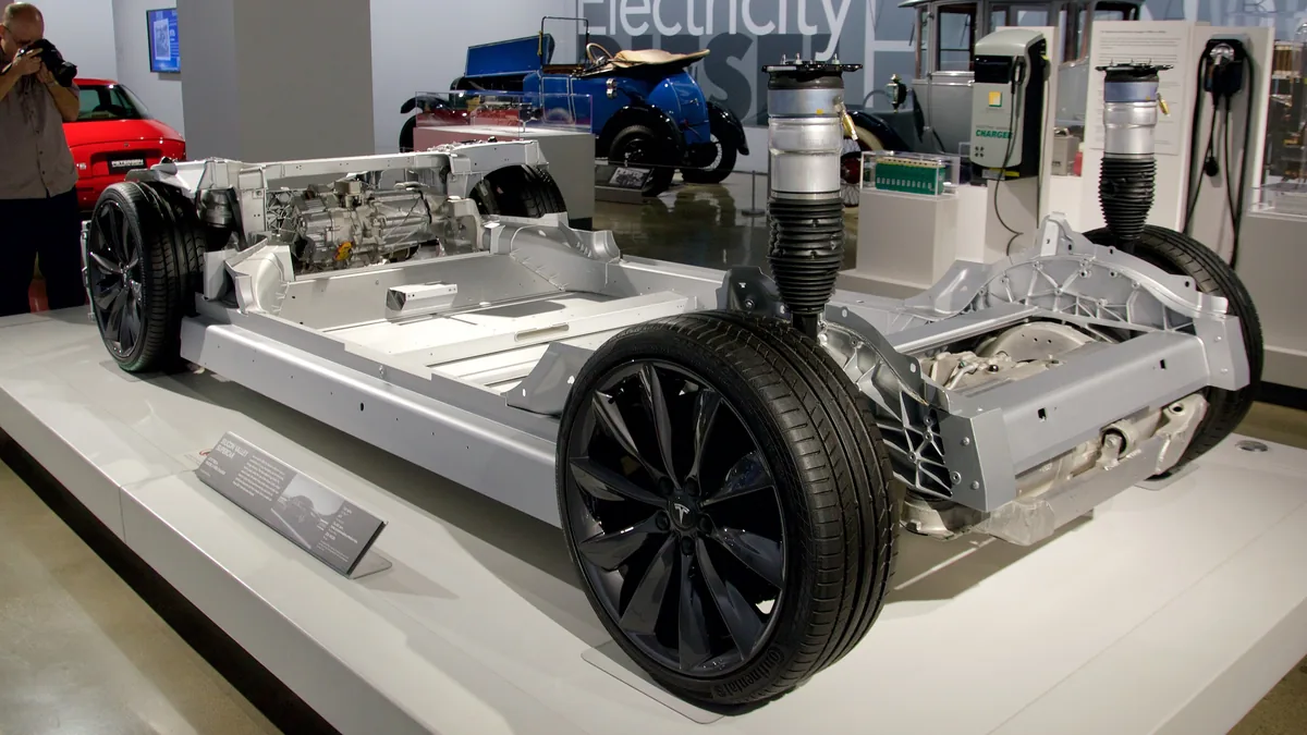 A Tesla Model S chassis with wheels, motors and the battery pack, on show at a car museum