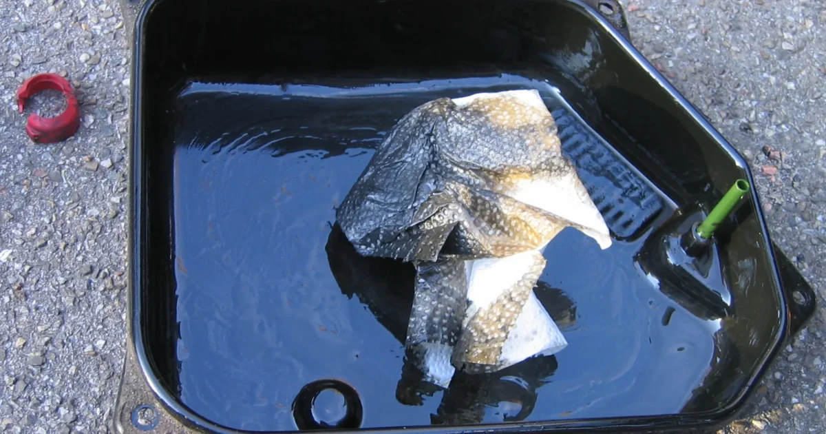 A removed automatic-transmission oil pan with visible deposits inside.