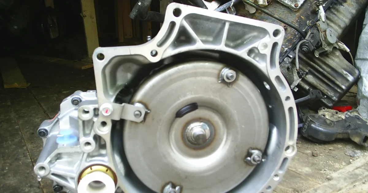 A silver automatic transmission seen from the front, with the round torque converter in the bell housing