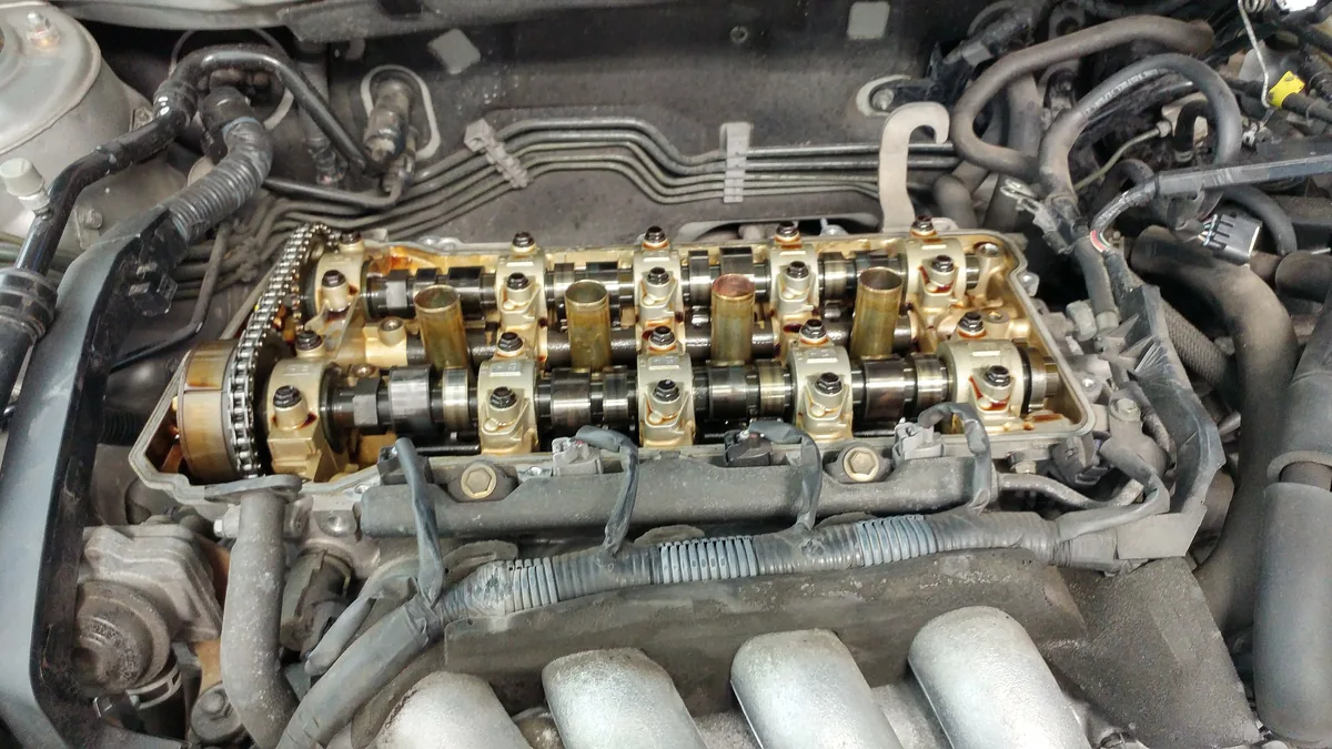 An engine with its valve cover removed, showing two camshafts and the timing chain under it