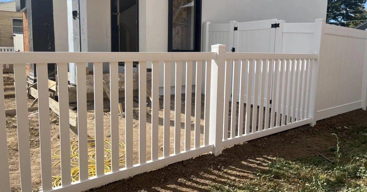 White open-picket vinyl fencing beside solid privacy panels and a matching gate near a house.