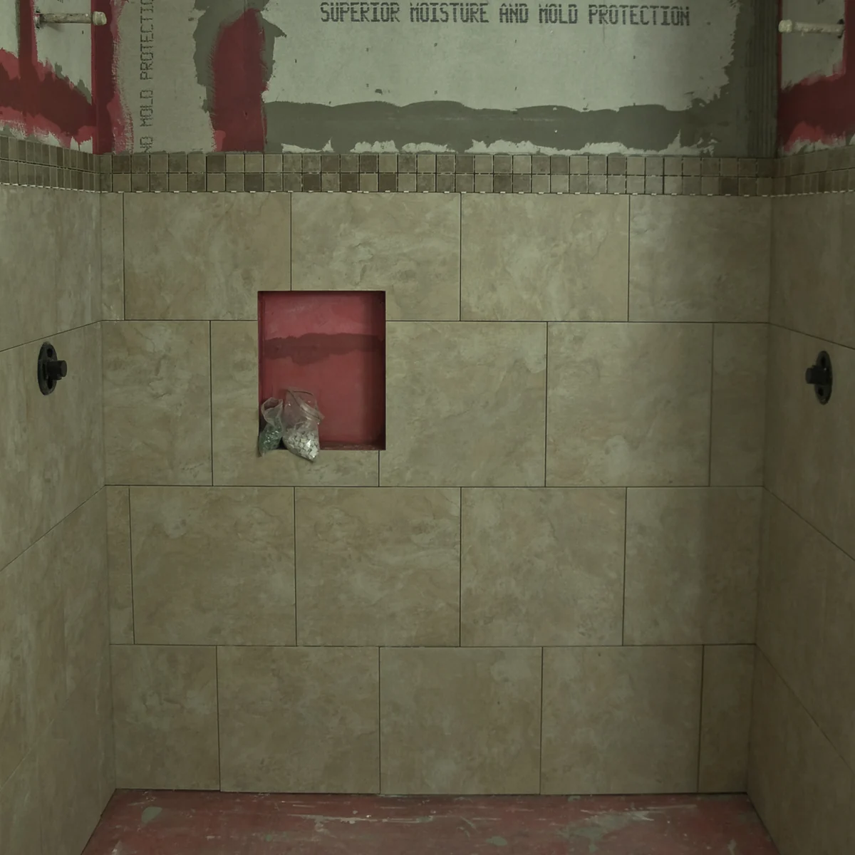 A shower under construction, with tiled lower walls, a niche and unfinished wall preparation above.