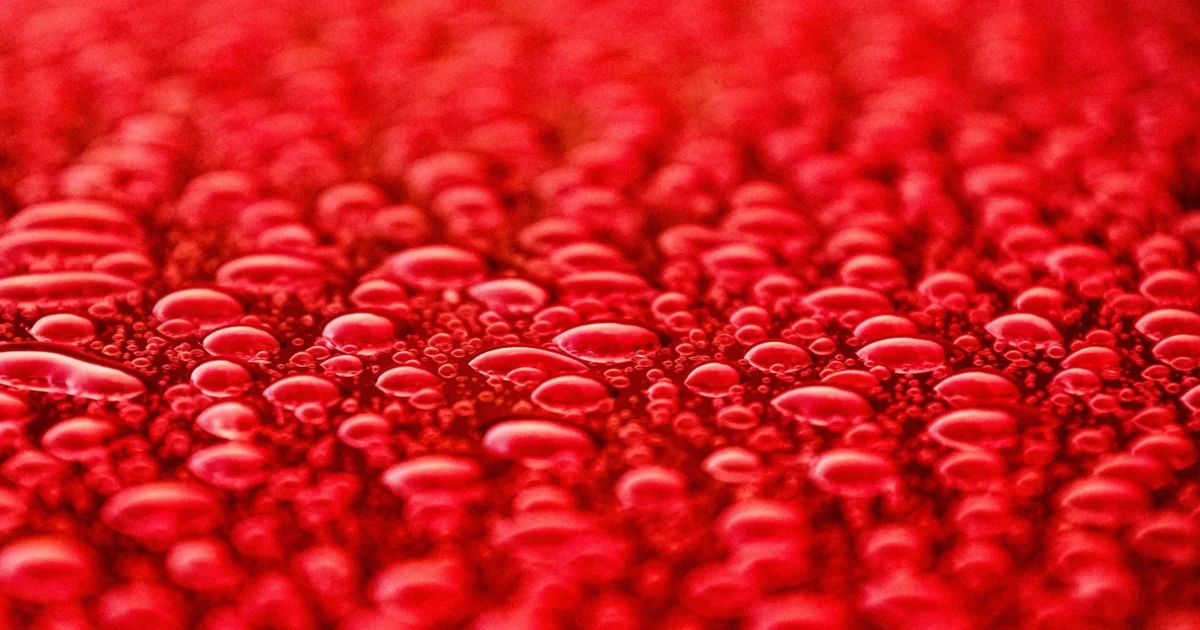 Rain sitting in round beads on glossy red car paint