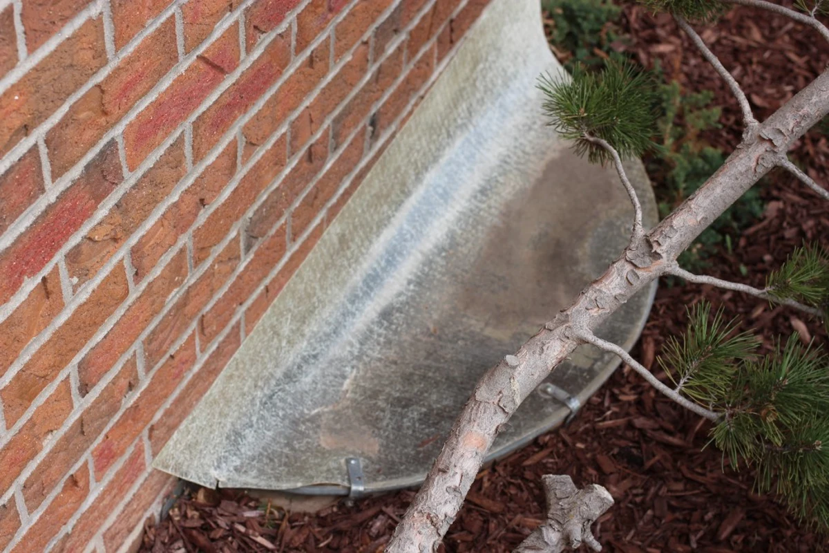 Clear sloping cover over a shallow basement window well.