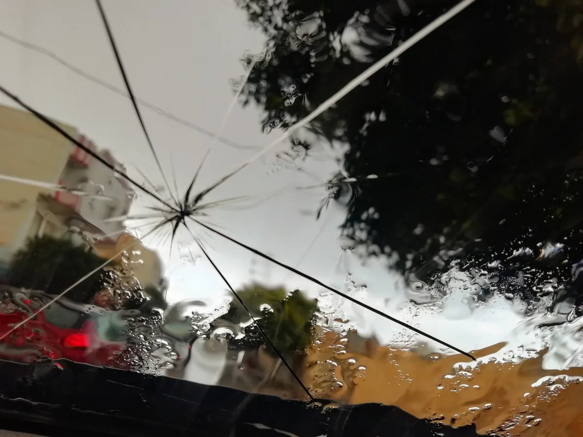 A windshield seen from inside with a small impact point and long cracks running out from it